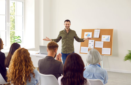 Young attractive happy man speaker talking about company stats and financial data analyzing growth...