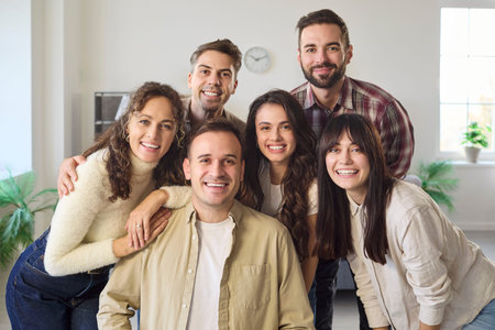 Friends group of adults smiling together at home. Warm indoor portrait in a living room, showing unity, support and positive energy for campaigns. Strong concept of friendship and teamwork.の写真素材
