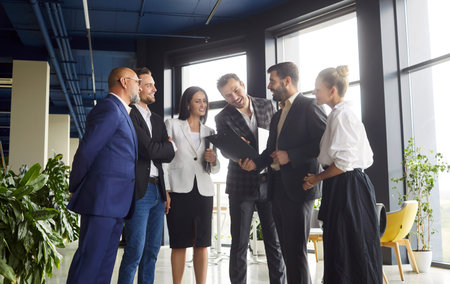 Open space office discussion of diverse business team standing together and talking. Professionals...