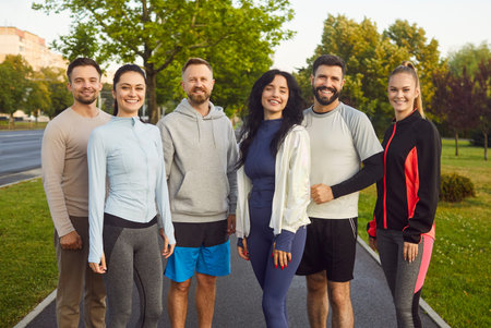Group of runners standing together after jogging in summer city park. Happy team of people training...