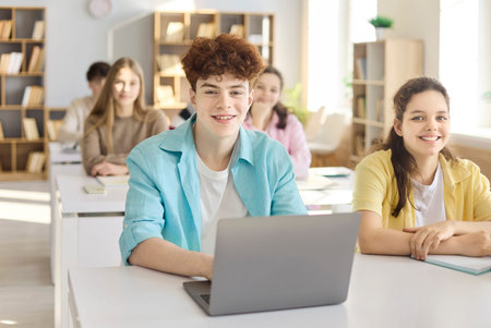 Students in classroom during lesson with laptop. Teenagers collaborate in school, focusing on study...