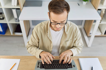 Writer typing on vintage typewriter in office, top view of desk with old analog machine and author....