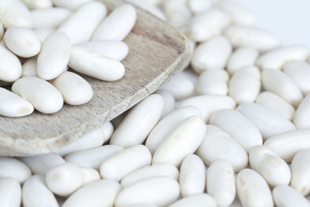 Beans on a wooden spoon and a white backgroundの写真素材