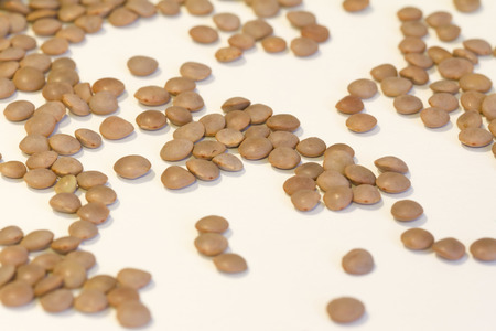 Lentil on a wooden spoon and white backgroundの写真素材