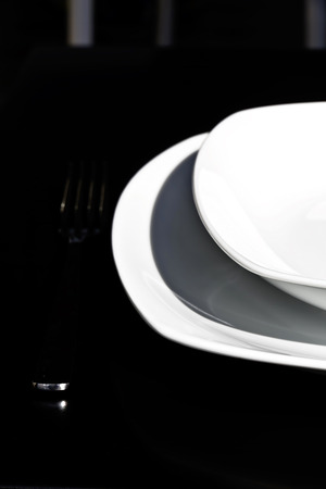 White plate and stainless steel cutlery on a black backgroundの写真素材