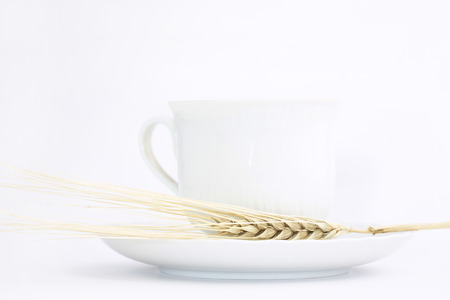 White ceramic teacup with ear of wheat on a white backgroundの写真素材