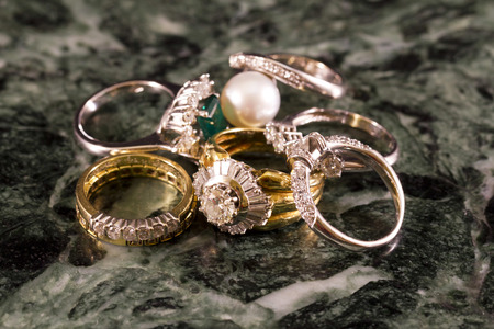 Precious jewels, rings with diamonds, emeralds and corals on green marbleの写真素材