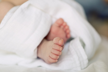 Close up picture of new born baby feet on a white sheet