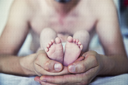 Baby feet cupped into father handsの写真素材