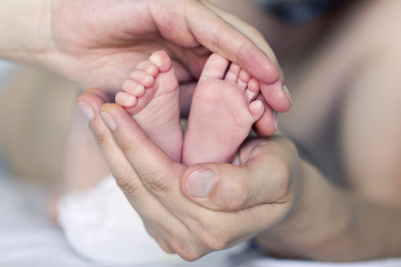 Baby feet cupped into father handsの写真素材