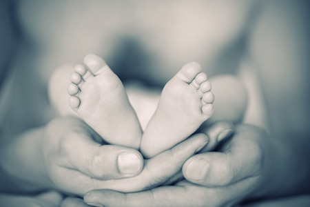 Baby feet cupped into father handsの写真素材