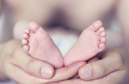 Baby feet cupped into father handsの写真素材
