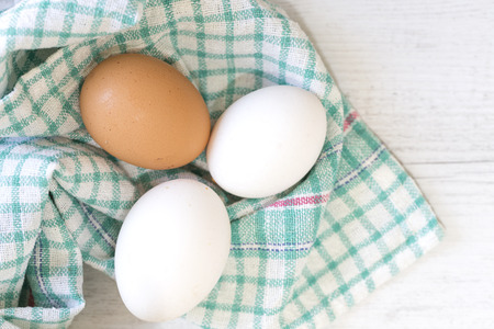 Group of three eggs on colored cloth and wooden table