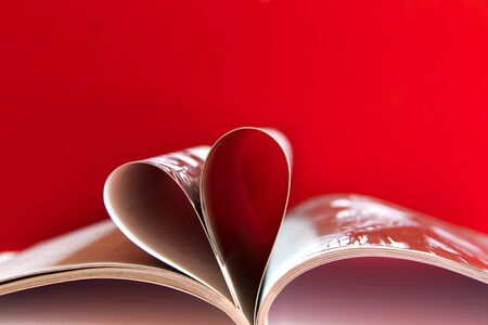 Embossed pages of book folded to make heart on red backgroundの写真素材