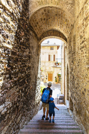 Asisisi, Umbria, July 16, 2019: Dad and son, tourists, stroll through the streets of Assisi, Umbria, Italyのeditorial素材
