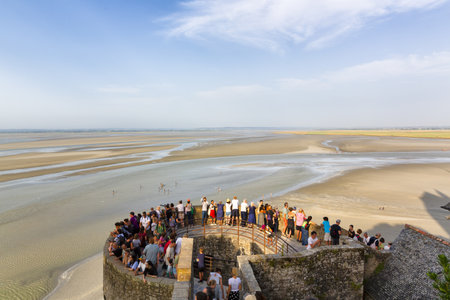 Tourists approach the iconic medieval abbey and fortress of Mont Saint Michel in Normandyの写真素材