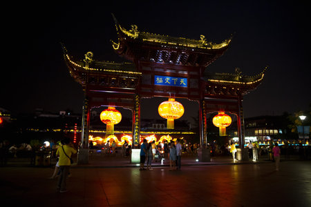 CHINA, NANJING - June 20, 2013: A beautifully illuminated traditional Chinese gate structure in the Confucius Temple area, stands prominently in a busy square in Nanjingの写真素材