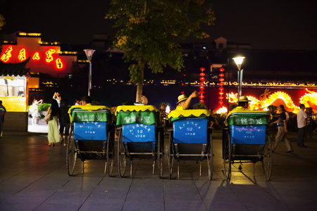 CHINA, NANJING - June 20, 2013: A row of rickshaws with blue and yellow canopies is parked, awaiting...