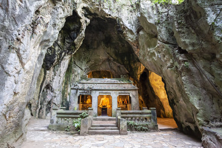 Grotto shrine with a glowing Buddhist statue and altar inside a limestone cave in the Marble Mountains, Da Nang, Vietnamの写真素材
