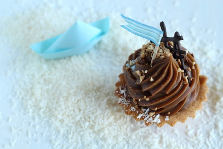 caramel cupcake with blue flag on desiccated coconut