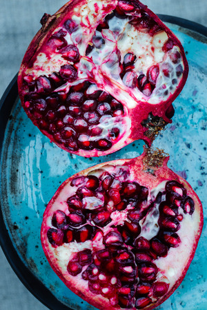 delicious, juicy half cut pomegranate on a blue handmade ceramics plateの写真素材