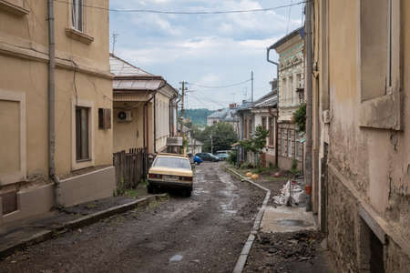 Damaged side street with old car in Chernivtsi, Ukraineの写真素材