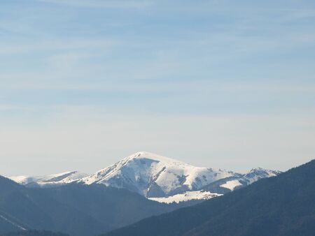 Morning landscape with mountains and blue sky. Evening sunset on the horizon of hills with white snow and cloudの写真素材