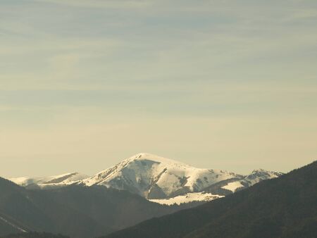Morning landscape with mountains and blue sky. Evening sunset on the horizon of hills with white snow and cloudの写真素材