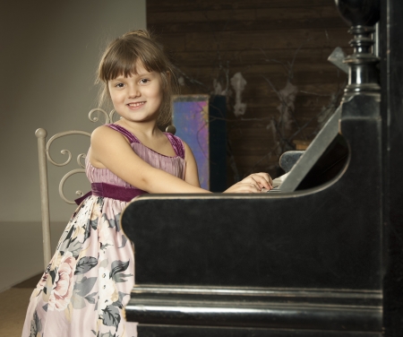 Cute little girl sits and play the pianoの写真素材