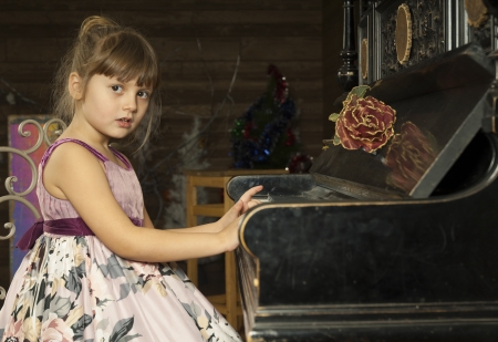 Cute little girl sits and play the pianoの写真素材
