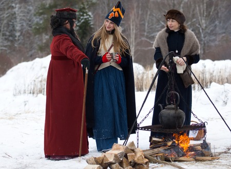 RUSSIA, APRELEVKA - FEBRUARY 7: Unidentified women stand near the fire and talk on reenactment of the Napoleonic maneuvers near the Aprelevka city, in 1812. Moscow region, Aprelevka, 7 February, 2015, Russiaのeditorial素材