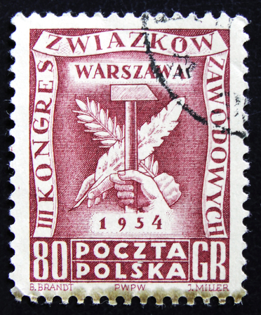MOSCOW, RUSSIA - APRIL 2, 2017: A post stamp printed in Poland shows hand, hammer, branch and feather pen, devoted to III Congress of complexes professionals, circa 1954のeditorial素材