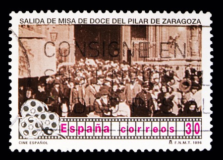 MOSCOW, RUSSIA - MAY 10, 2018: A stamp printed in Spain shows scene from Spanish Cinema "Salida de misa de doce del Pilar de Zaragoza", Spanish cinema serie, circa 1996のeditorial素材