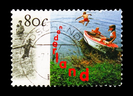 MOSCOW, RUSSIA - AUGUST 18, 2018: A stamp printed in Netherlands shows Swimming children with rowing boat, Holland Promotion serie, circa 1997のeditorial素材