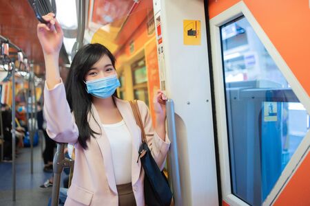 Asian woman in a protective mask or surgical mask standing in a train