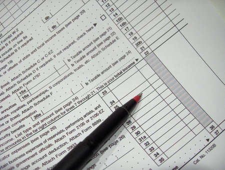 Red pen lies on copy of federal tax formの写真素材