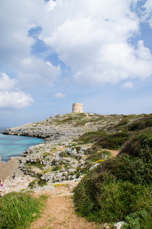 Photograph of a wonderful landscape in Alcaufar, Menorca. A watchtower on the top of the rocks next to the sea with a beach entering.の写真素材