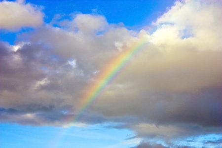 Beautiful rainbow in bright blue sky with cloud after summer rain. Soft focus.の写真素材