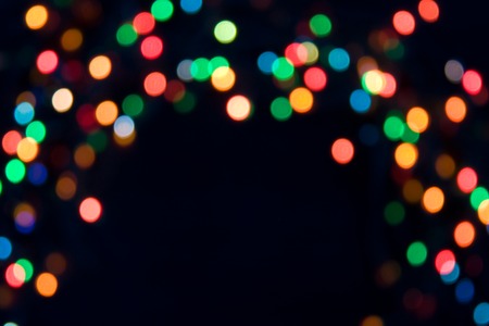 Christmas or Halloween vivid abstract concept. Bright spots of red, yellow, green and blue lights on blackground. Bokeh. Soft focus. Round shapes.の写真素材