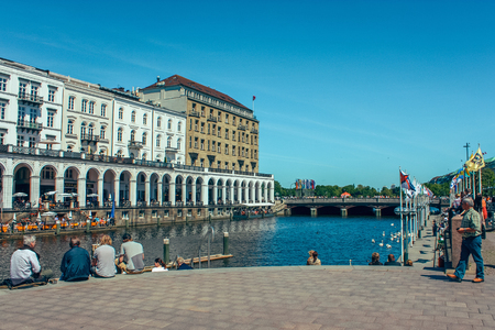 A picturesque lake Alstersee in the central historical district Roterbaum of Hamburg, Germany.June 2010. People on the steps of the stairs fed swans, ducks, geese. Popular vacation spot, health trailのeditorial素材