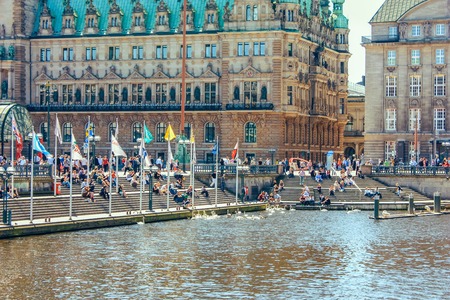 A picturesque lake Alstersee in the central historical district Roterbaum of Hamburg, Germany.June 2010. People on the steps of the stairs fed swans, ducks, geese. Popular vacation spot, health trailのeditorial素材