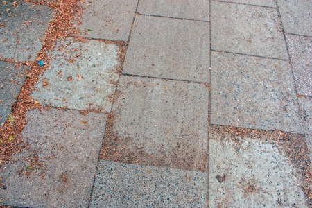 Large granite slabs on a pedestrian walkway with dry leaves and small debrisの写真素材