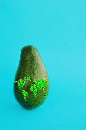 Green ripe avocado fresh harvest with a world map to illustrate a healthy lifestyle, emblm proper...