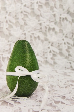 Green avocado measuring body with white silk belt bow to lace dress.の写真素材