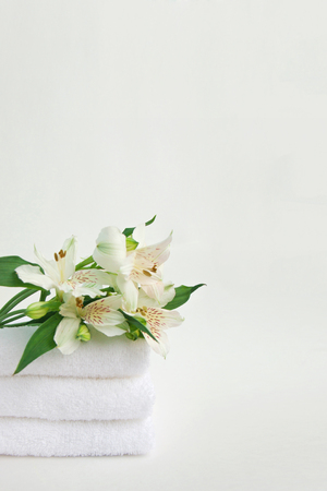 Beautiful bouquet of alstroemeria flower on stack of three clean white spa salon bath towels isolated on white background. Front view copy space close upの写真素材