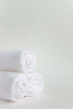 Three rolls of clean white spa salon bath towels isolated on white background. Front view copy space close upの写真素材