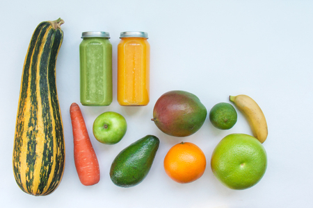 Creative background smoothie juice summer fruits vegetables. Avocado,apple, carrot banana persimmon zucchini orange lime mango white paper.の写真素材