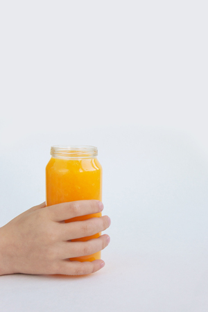 Creative background bottle of two orange juice in the hands of a child isolated on white paper.の写真素材