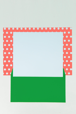 Beautiful background of paper of color living coral polka dot and white with green envelope with copy space for text. Top view, close up flat lay. Card concept.の写真素材