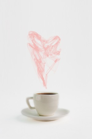 White espresso coffee cup saucer with heart shaped steam on paper background, front view copy space close upの写真素材